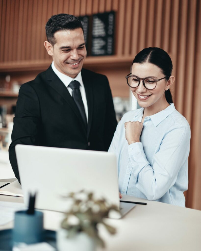 two smiling businesspeople using a laptop together in an office.jpg